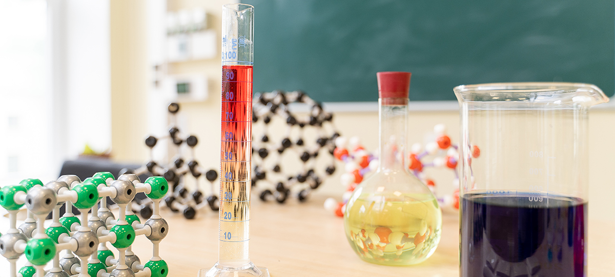Image of a chemistry class with tubes on the table and flasks filled with chemicals
